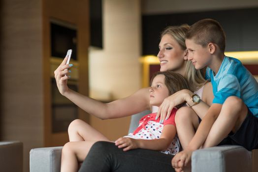 Happy family siting on sofa and using cell phone for video call  at home