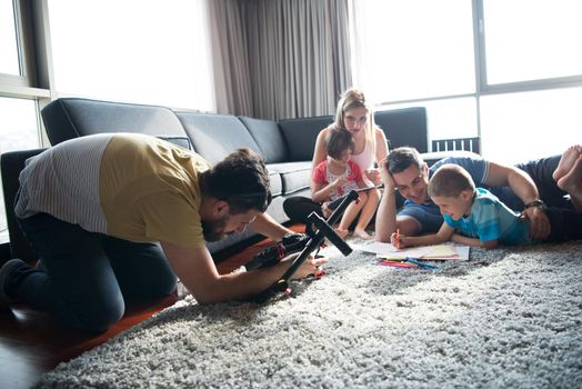 Happy Young Family Playing Together at home on the floor using a tablet and a children's drawing set