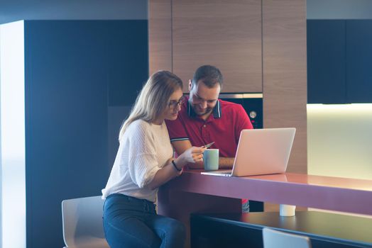 happy young couple buying online using laptop a computer and a credit card in their luxury home villa