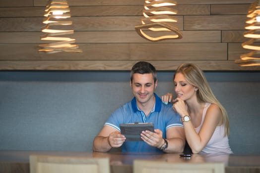 Young couple using tablet computer at luxury home together, looking at screen, smiling.