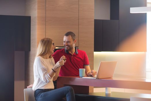 happy young couple buying online using laptop a computer and a credit card in their luxury home villa