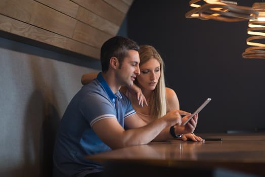 Young couple using tablet computer at luxury home together, looking at screen, smiling.