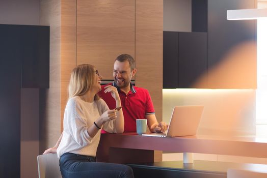 happy young couple buying online using laptop a computer and a credit card in their luxury home villa