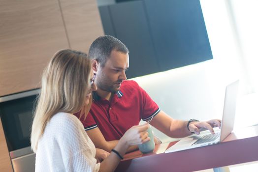 happy young couple buying online using laptop a computer and a credit card in their luxury home villa