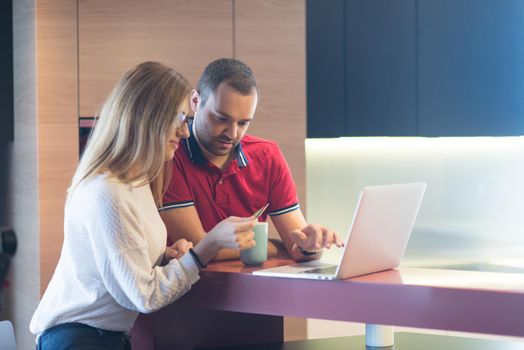 happy young couple buying online using laptop a computer and a credit card in their luxury home villa