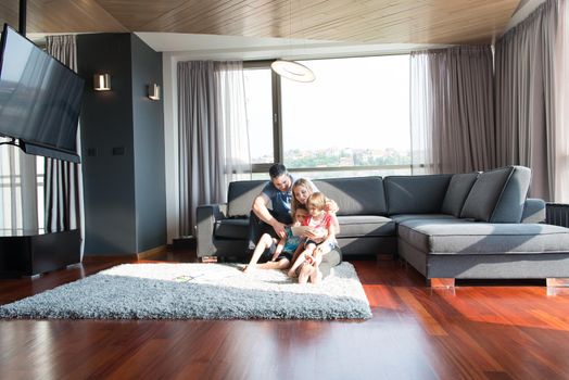 Happy Young Family Playing Together with tablet at home sitting on the sofa