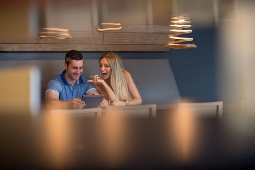 Young couple using tablet computer at luxury home together, looking at screen, smiling.