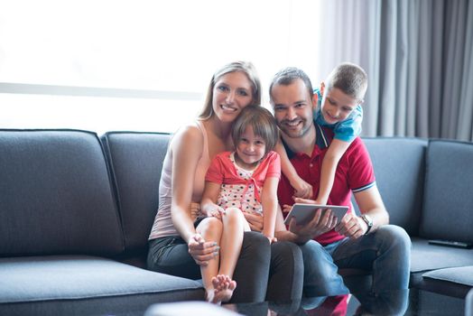 Happy Young Family Playing Together with tablet at home sitting on the sofa