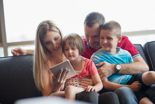 Happy Young Family Playing Together with tablet at home sitting on the sofa