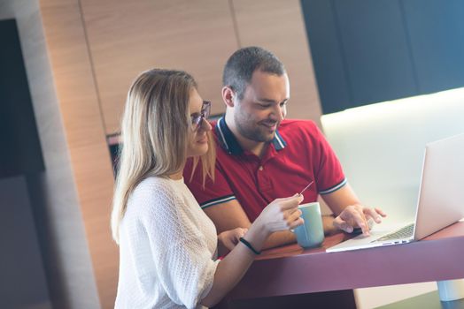 happy young couple buying online using laptop a computer and a credit card in their luxury home villa