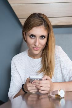 young happy woman sitting at the table and using mobile phone at luxury home