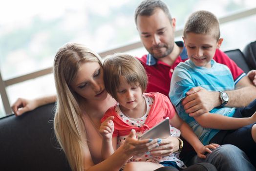 Happy Young Family Playing Together with tablet at home sitting on the sofa