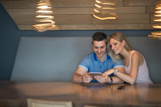 Young couple using tablet computer at luxury home together, looking at screen, smiling.