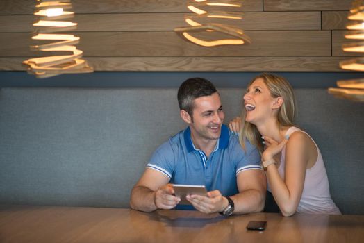 Young couple using tablet computer at luxury home together, looking at screen, smiling.