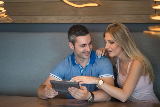 Young couple using tablet computer at luxury home together, looking at screen, smiling.