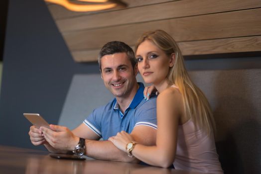 Young couple using tablet computer at luxury home together, looking at screen, smiling.