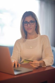 Young woman holding credit card and using laptop computer. Online shopping concept