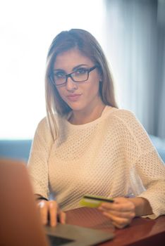 Young woman holding credit card and using laptop computer. Online shopping concept