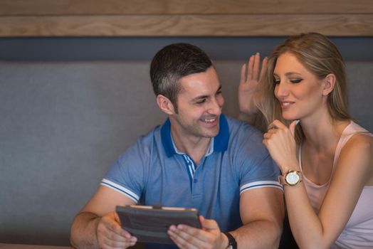 Young couple using tablet computer at luxury home together, looking at screen, smiling.