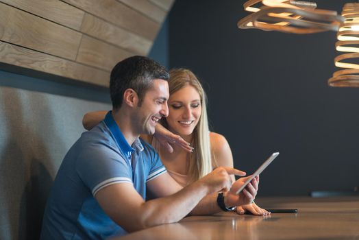 Young couple using tablet computer at luxury home together, looking at screen, smiling.