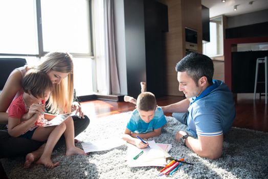 Happy Young Family Playing Together at home on the floor using a tablet and a children's drawing set