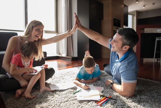 Happy Young Family Playing Together at home on the floor using a tablet and a children's drawing set