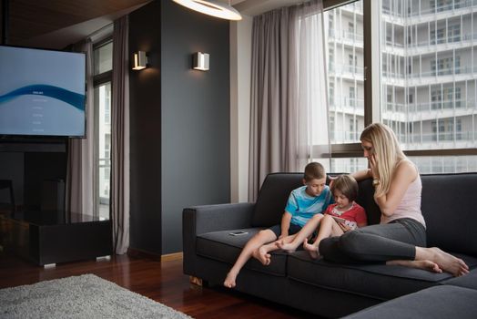 Happy Young Family Playing Together with tablet at home sitting on the sofa