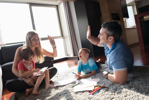 Happy Young Family Playing Together at home on the floor using a tablet and a children's drawing set