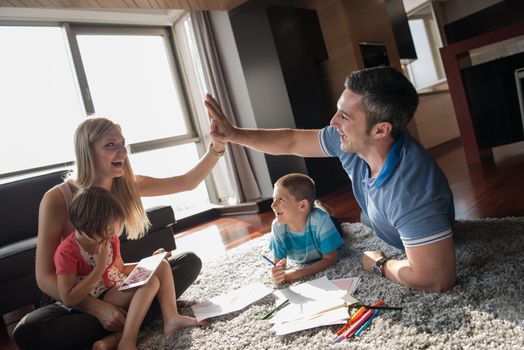 Happy Young Family Playing Together at home on the floor using a tablet and a children's drawing set