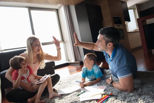 Happy Young Family Playing Together at home on the floor using a tablet and a children's drawing set