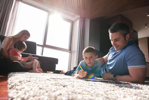 Happy Young Family Playing Together at home on the floor using a tablet and a children's drawing set