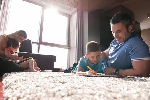 Happy Young Family Playing Together at home on the floor using a tablet and a children's drawing set