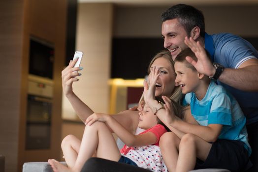 Happy family siting on sofa and using cell phone for video call  at home