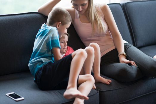 Happy Young Family Playing Together with tablet at home sitting on the sofa