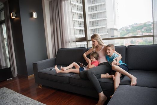 Happy Young Family Playing Together with tablet at home sitting on the sofa