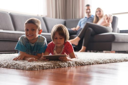 Happy Young Family Playing Together at home.kids using tablet on the floor