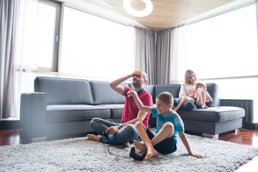 Happy family. Father, mother and children playing a video game Father and son playing video games together on the floor