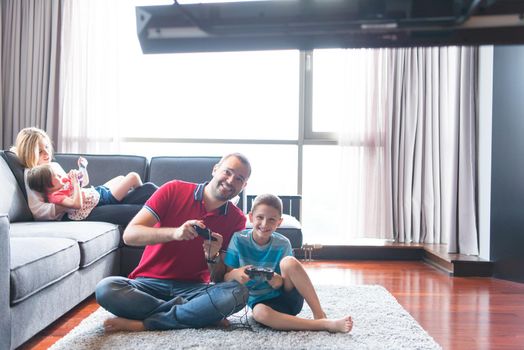 Happy family. Father, mother and children playing a video game Father and son playing video games together on the floor