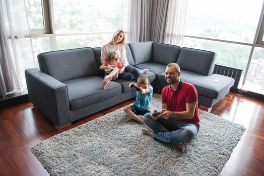 Happy family. Father, mother and children playing a video game Father and son playing video games together on the floor