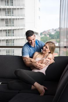 young handsome couple enjoys hugging on the sofa in their luxury home villa