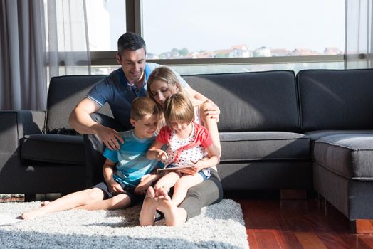 Happy Young Family Playing Together with tablet at home sitting on the sofa