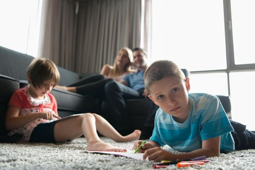 Happy Young Family Playing Together at home on the floor using a tablet and a children's drawing set