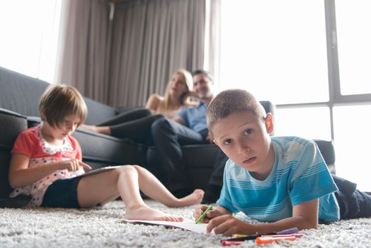 Happy Young Family Playing Together at home on the floor using a tablet and a children's drawing set