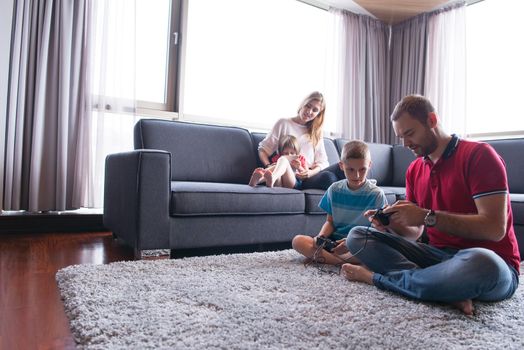 Happy family. Father, mother and children playing a video game Father and son playing video games together on the floor