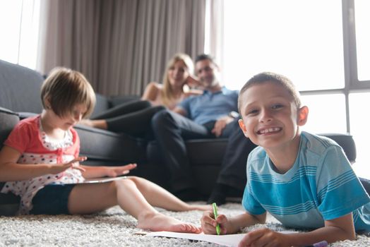 Happy Young Family Playing Together at home on the floor using a tablet and a children's drawing set