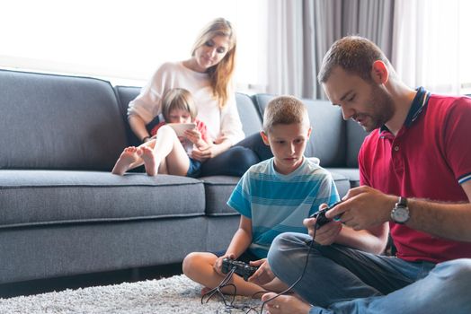 Happy family. Father, mother and children playing a video game Father and son playing video games together on the floor