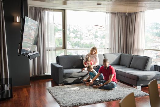 Happy family. Father, mother and children playing a video game Father and son playing video games together on the floor