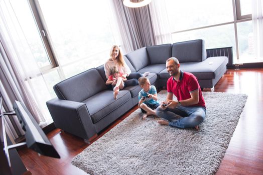 Happy family. Father, mother and children playing a video game Father and son playing video games together on the floor