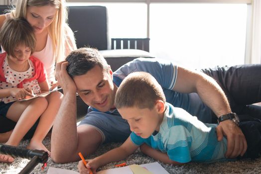 Happy Young Family Playing Together at home on the floor using a tablet and a children's drawing set