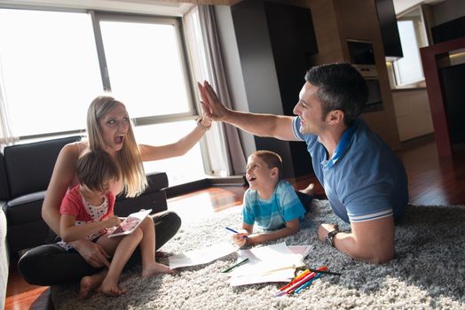 Happy Young Family Playing Together at home on the floor using a tablet and a children's drawing set